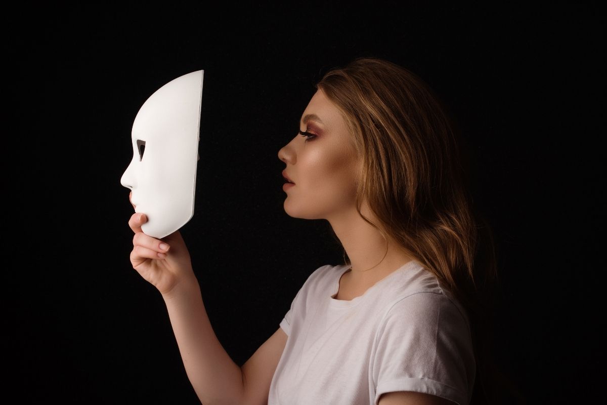 Femme qui va porter un masque cachant sa fatigue intérieure et sa fidélité à elle même, symbolisant le people pleasing